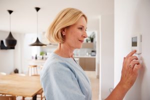 woman adjust smart thermostat