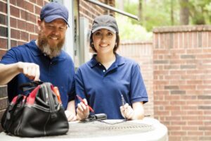 male-and-female-ac-technician-working-outside-with-tools-on-condenser