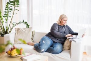 plus-size-woman-sitting-on-couch-looking-at-laptop